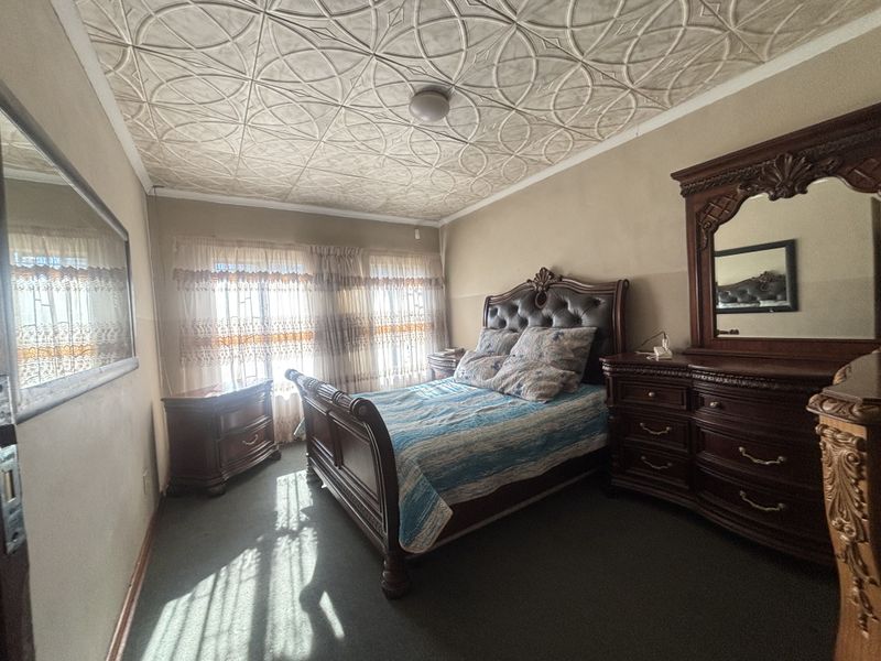 A bedroom featuring a unique decorative pressed metal ceiling and carpeted flooring, offering a classic aesthetic with potential for modern updates.
