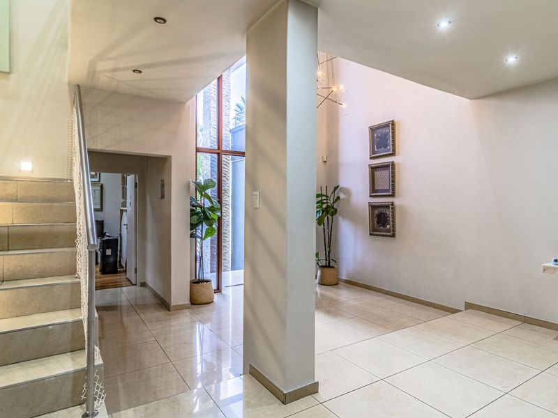 Spacious entrance hall featuring tiled flooring, a modern staircase, and a striking full-height window that allows for abundant natural light.