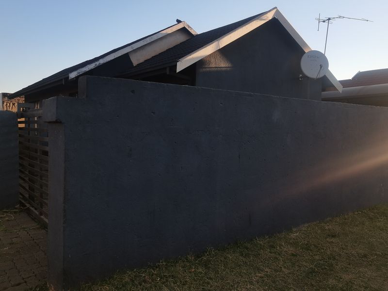 A view of the property exterior featuring a dark painted boundary wall, tiled roof, and satellite dish installation.