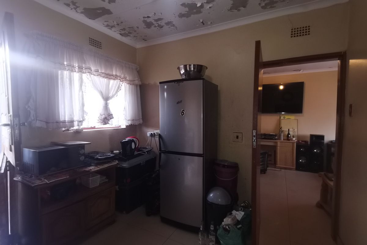 A kitchen area featuring tiled flooring and ventilation bricks, currently requiring significant ceiling repairs and cosmetic updates.