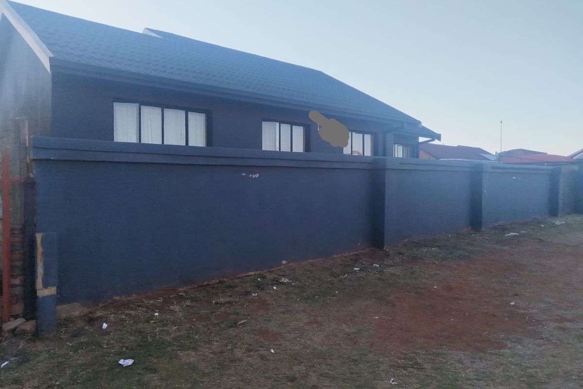 Exterior view of the property featuring a dark-painted perimeter wall and a tiled roof structure.