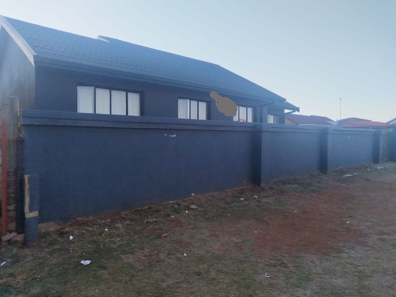 Exterior view of the property featuring a dark-painted perimeter wall and a tiled roof structure.