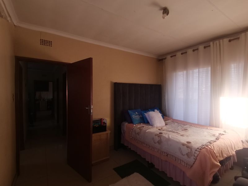 A standard bedroom featuring tiled flooring, neutral wall tones, and natural light through window curtains.