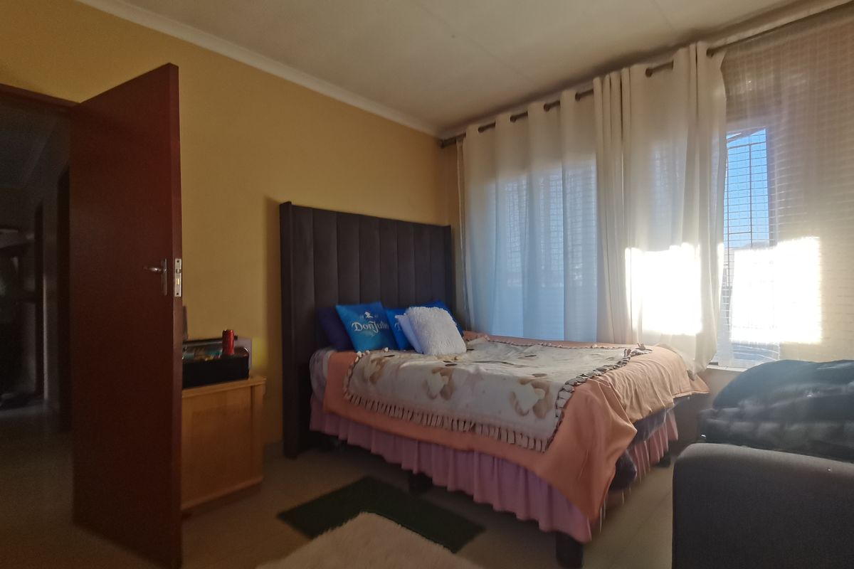 A standard bedroom featuring tiled flooring and large windows with curtain rails, providing natural light and a functional layout.