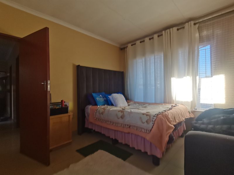 A standard bedroom featuring tiled flooring and large windows with curtain rails, providing natural light and a functional layout.