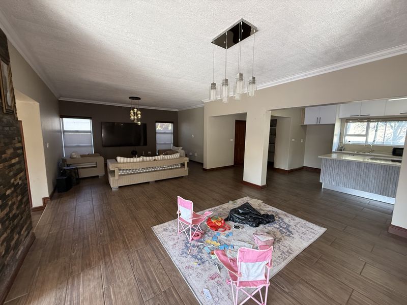 Spacious open-plan living area featuring tiled floors, a modern kitchen island, and a brick feature wall, creating a versatile and connected living space.