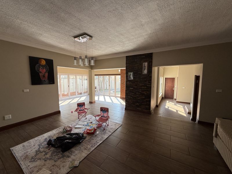 Spacious open-plan living area featuring a stone-clad feature wall, tiled flooring, and large sliding glass doors providing ample natural light.