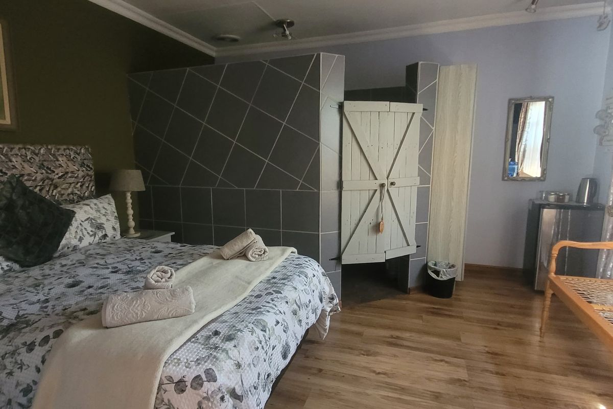 A bedroom featuring laminate flooring, a tiled partition wall, and a rustic timber door, offering a functional layout with integrated storage space.
