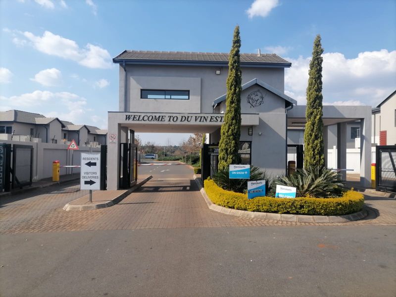 The main entrance gatehouse of Du Vin Estate, featuring a secure boom gate system, paved driveway, and well-maintained landscaped surroundings.