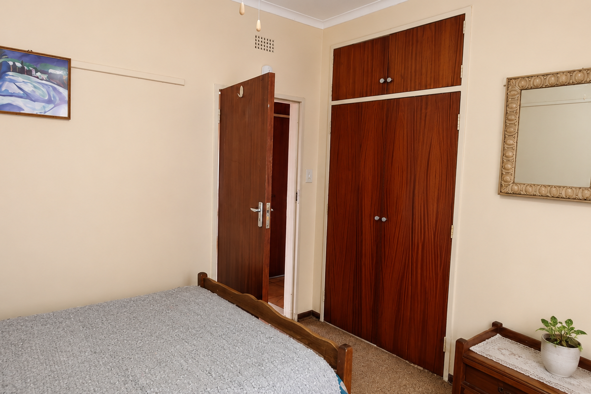 A bedroom featuring built-in wooden wardrobes, carpeted flooring, and neutral wall finishes, offering a functional space with classic storage solutions.