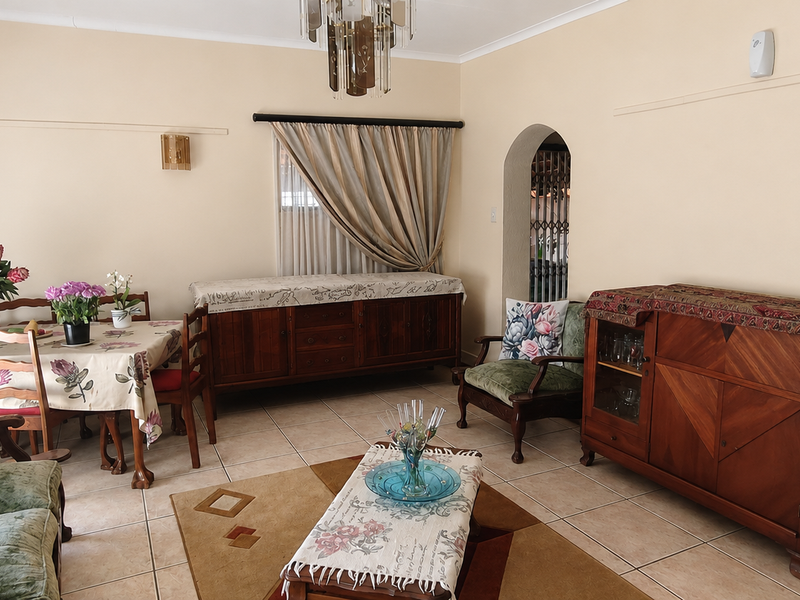 An open-plan living and dining area featuring tiled flooring, a decorative archway, and neutral wall finishes.