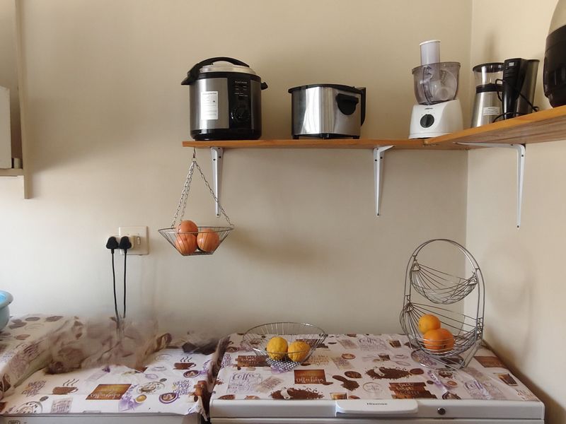 A functional scullery or utility area featuring wall-mounted shelving and built-in cabinetry, providing additional storage and workspace for kitchen tasks.