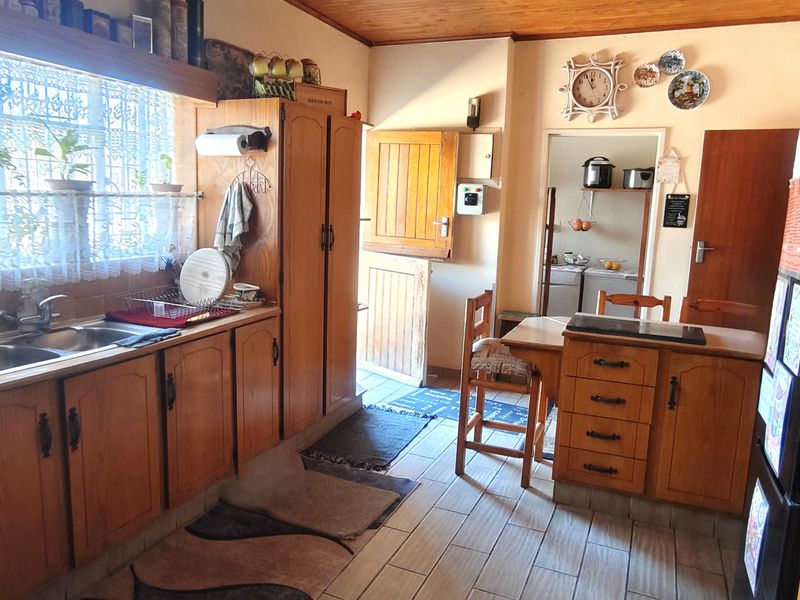 A functional kitchen featuring wooden cabinetry, a double sink, built-in oven, and tiled flooring, with a stable door leading to the exterior.