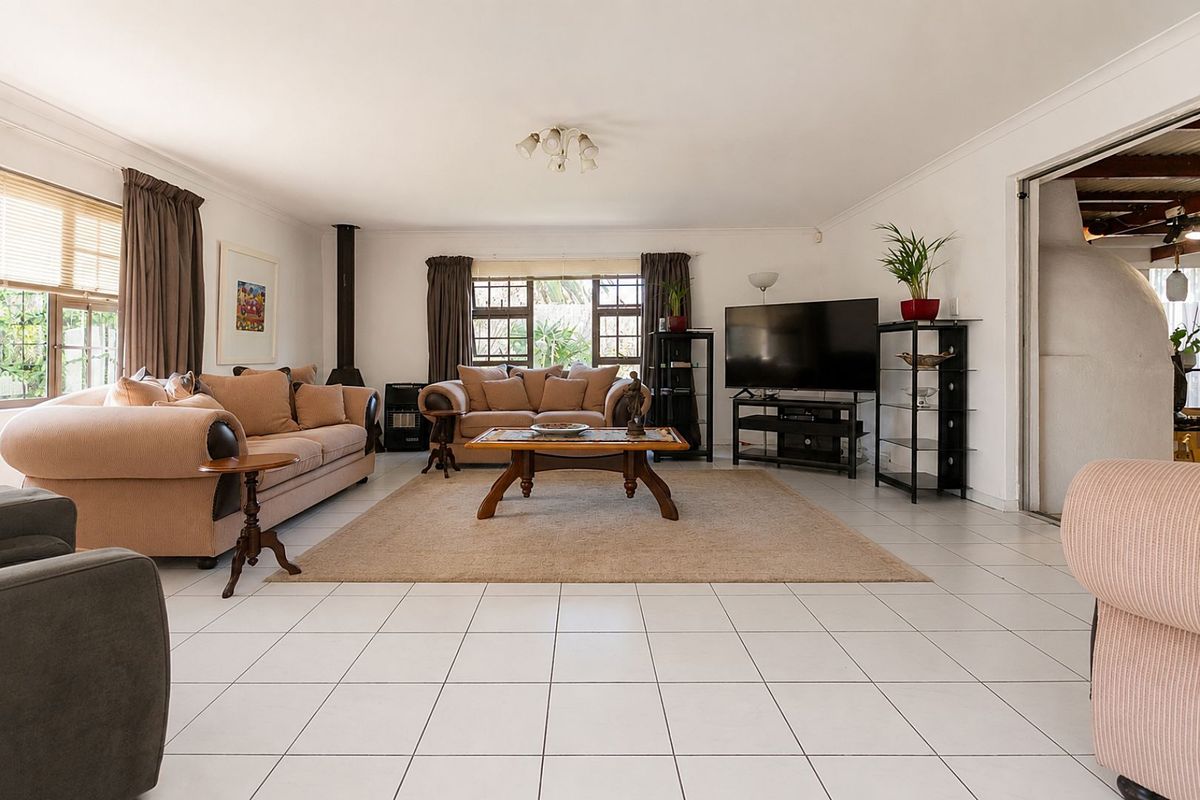 Spacious living room featuring tiled flooring, a freestanding fireplace, and large windows allowing for natural light.