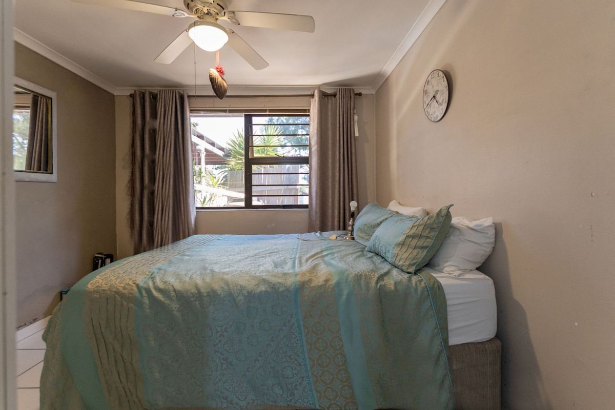 A functional bedroom featuring a ceiling fan, security bars on the window, and tiled flooring.