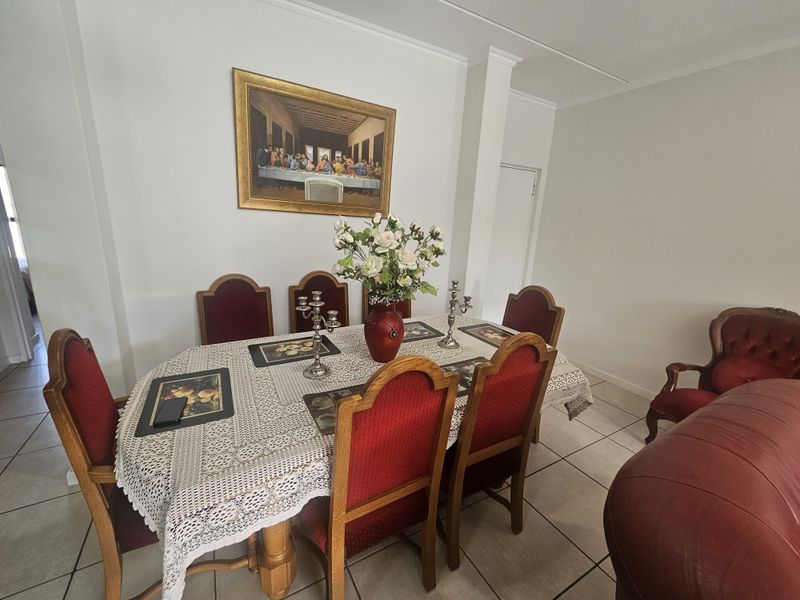 A dining room featuring neutral walls, crown molding, and ceramic floor tiles, providing a functional space for family meals.