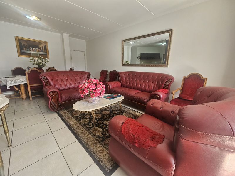 A spacious living room featuring neutral tiled flooring and recessed ceiling lighting, providing a functional base for a comfortable seating area.