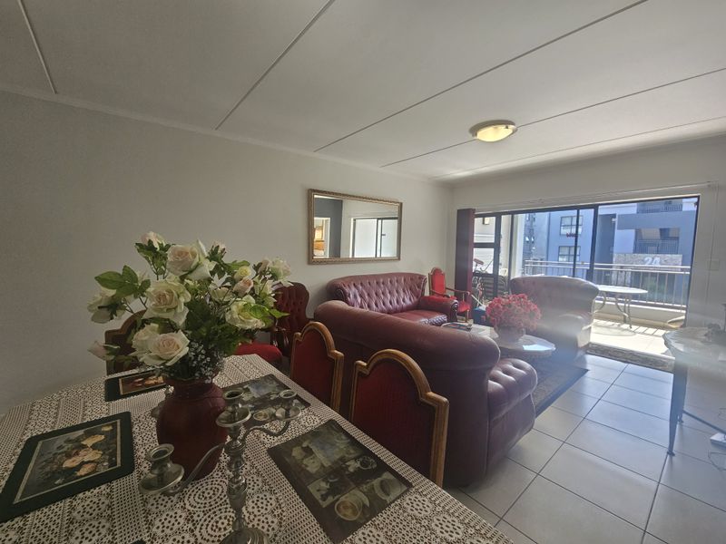 Open-plan living and dining area featuring tiled flooring and large sliding glass doors leading to an attached balcony.