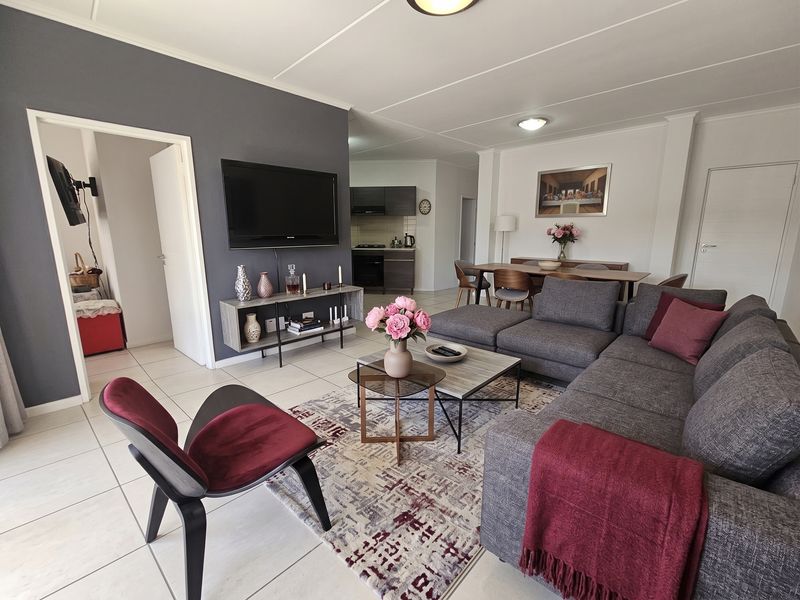 Spacious open-plan living and dining area featuring tiled floors, neutral walls, and a functional kitchen with built-in appliances.