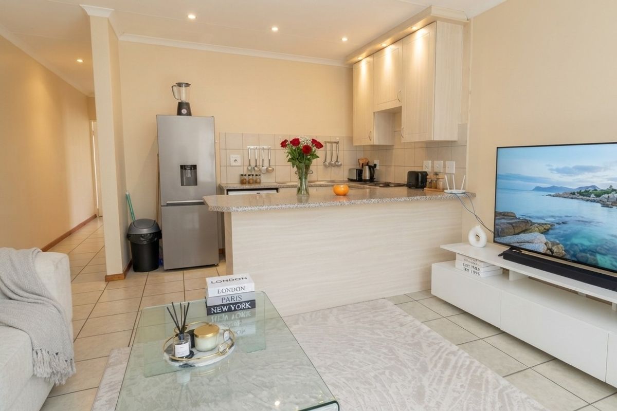 Open-plan living area featuring a functional kitchen with granite countertops, breakfast bar, and neutral tiled flooring throughout.