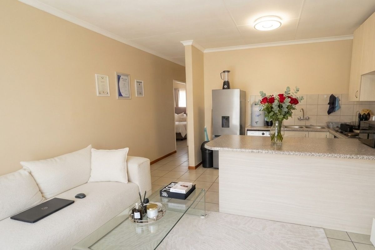 Open-plan living area featuring a functional kitchen with granite countertops and tiled flooring, seamlessly connected to the lounge space.