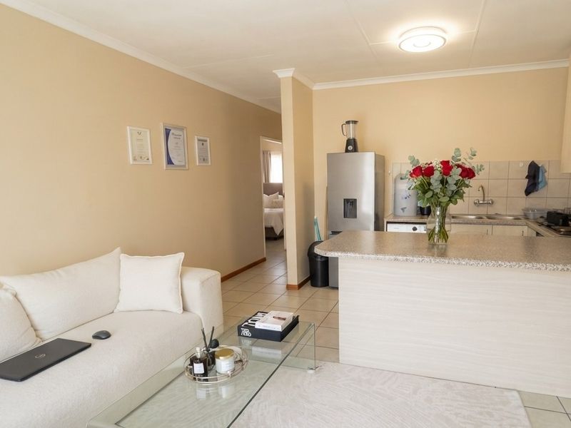 Open-plan living area featuring a functional kitchen with granite countertops and tiled flooring, seamlessly connected to the lounge space.