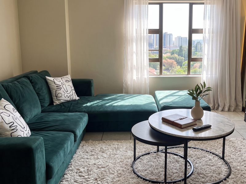 A bright living room featuring tiled flooring and a large window with natural light, offering an urban view.