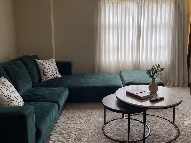A comfortable living room featuring tiled flooring and floor-to-ceiling sheer curtains, providing a bright and inviting atmosphere.