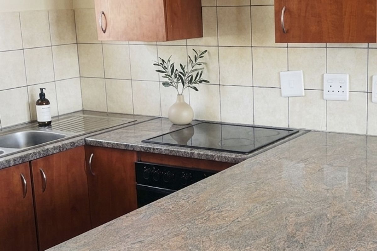 A functional kitchen featuring wood-tone laminate cabinetry, granite-look laminate countertops, a ceramic tile backsplash, and integrated electric cooking appliances.