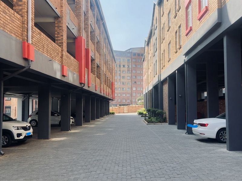 A view of the apartment complex driveway featuring covered parking bays and modern brick facade architecture.