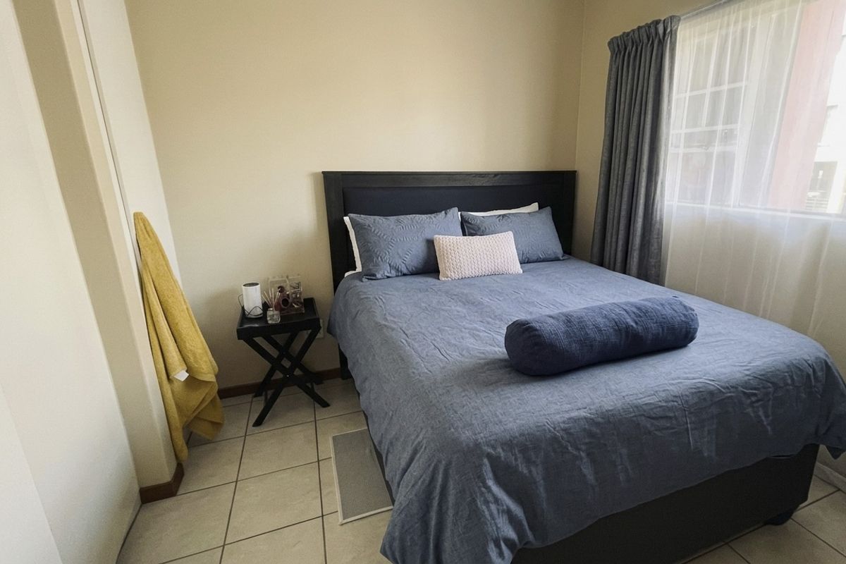 A functional bedroom featuring tiled flooring and a built-in cupboard, offering a neutral space ready for personalization.
