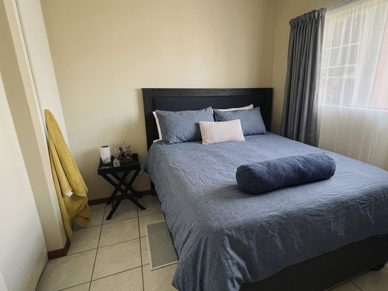 A functional bedroom featuring tiled flooring and a built-in cupboard, offering a neutral space ready for personalization.