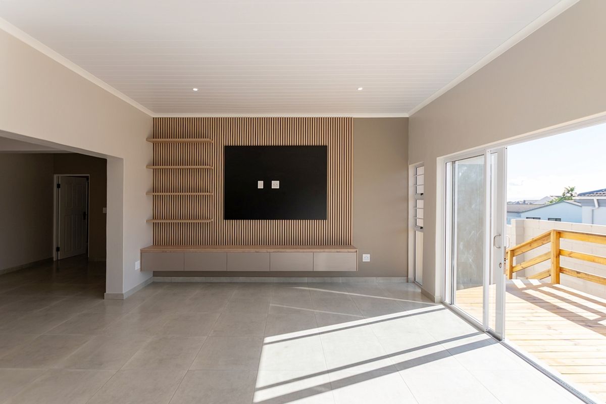 Modern living room featuring a stylish slatted timber feature wall with built-in cabinetry, large format floor tiles, and direct access to an outdoor deck.
