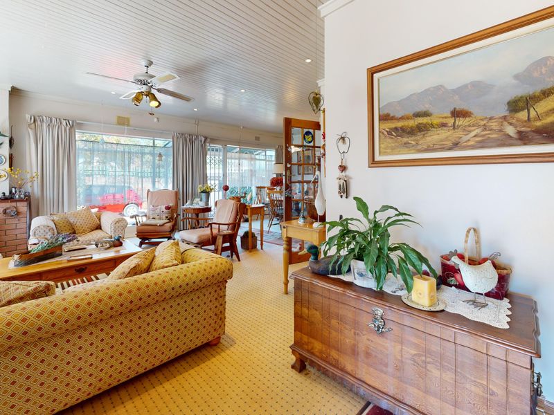 Spacious living room featuring a brick fireplace, wood-paneled ceiling with a fan, and large sliding glass doors providing natural light.