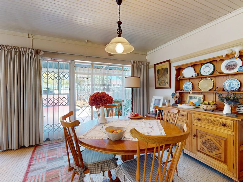 A dining room featuring a tongue and groove ceiling, pendant lighting, and sliding glass doors with security gates leading to the outdoor area.