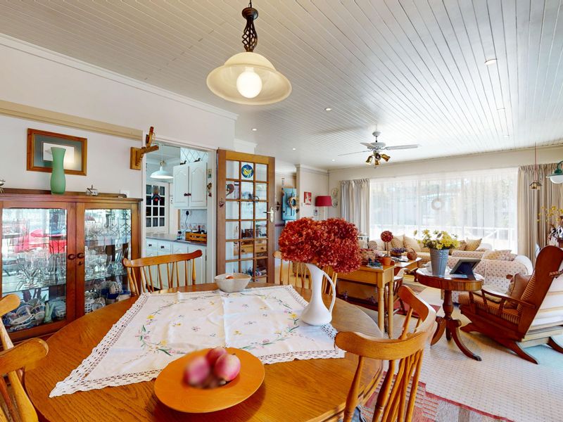 Spacious open-plan living and dining area featuring a timber tongue and groove ceiling, ceiling fan, and direct access to the kitchen via french doors.