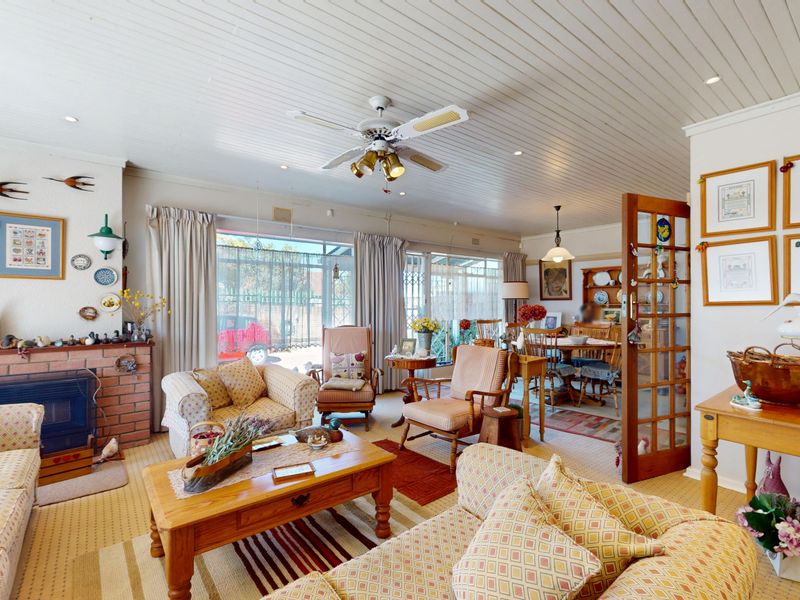 Open-plan living and dining area featuring a brick fireplace, timber-paneled ceiling, and direct access to the outdoor space through sliding glass doors.