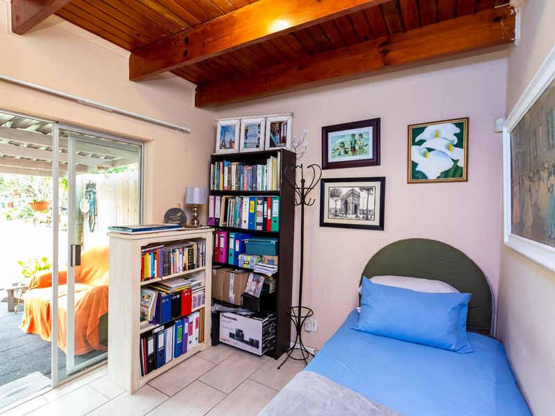 A bedroom featuring exposed timber ceiling beams, tiled flooring, and a sliding glass door providing direct access to the outdoor patio area.