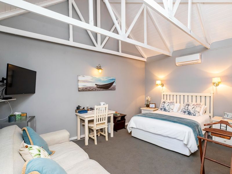 Spacious bedroom featuring a high vaulted ceiling with exposed white trusses, wall-mounted air conditioning, and neutral finishes.