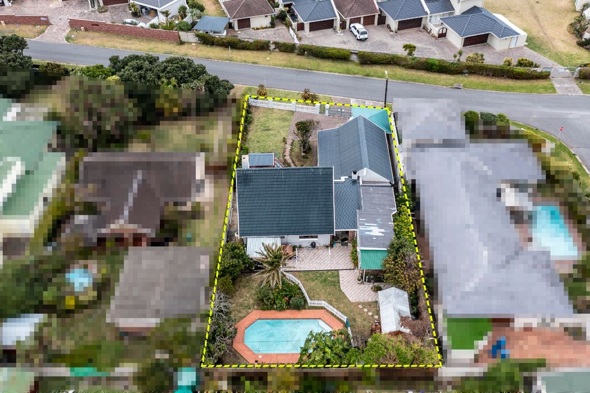 Aerial view of the residential property showing the house layout, swimming pool, paved patio areas, and surrounding garden within the fenced boundary.