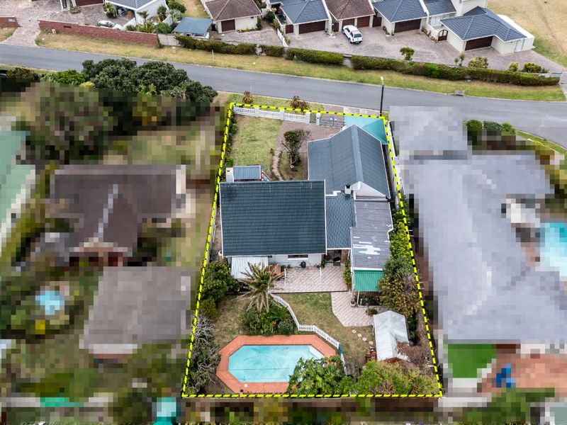 Aerial view of the residential property showing the house layout, swimming pool, paved patio areas, and surrounding garden within the fenced boundary.