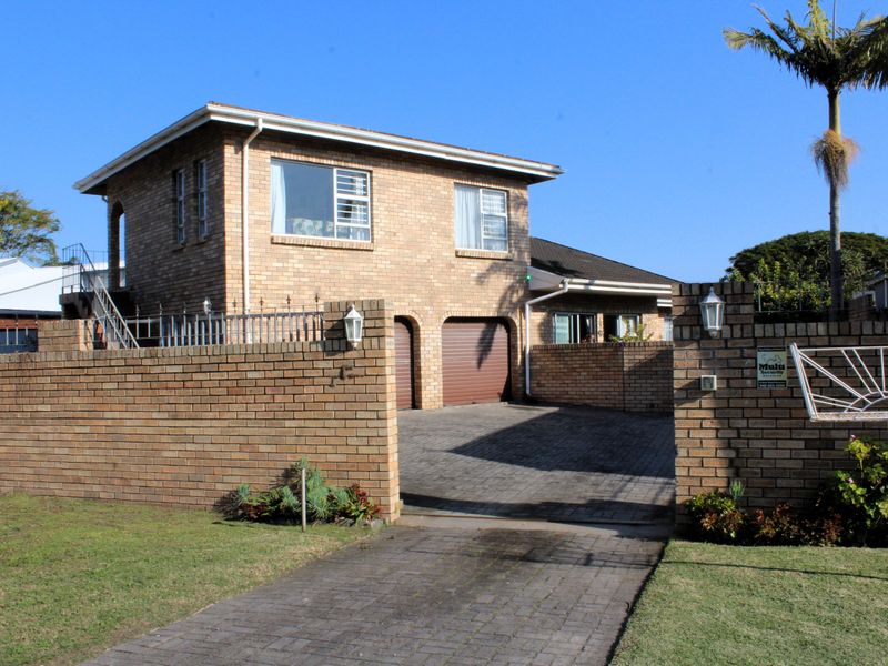 A well-maintained double-story brick house featuring a paved driveway, double garage, and secure perimeter walling.