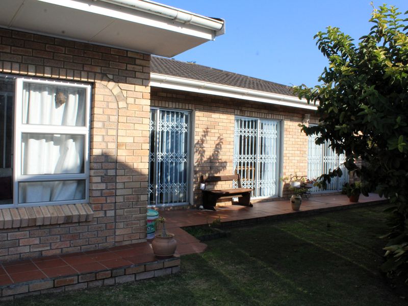 Rear view of a face brick house featuring a tiled patio area with sliding glass doors and security gates.