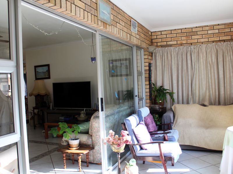 A covered patio area featuring exposed brick walls, tiled flooring, and large sliding glass doors that connect to the interior living space.