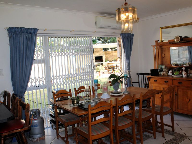 A dining area featuring tiled flooring, a chandelier, and a sliding glass door with a security gate leading to the outdoor patio.