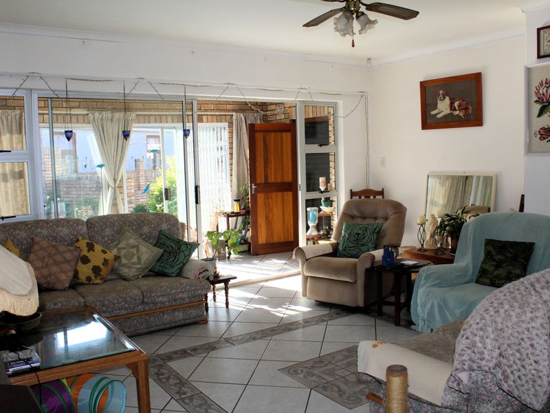 Spacious living room featuring tiled flooring, a ceiling fan, and large sliding glass doors providing access to an outdoor patio area.