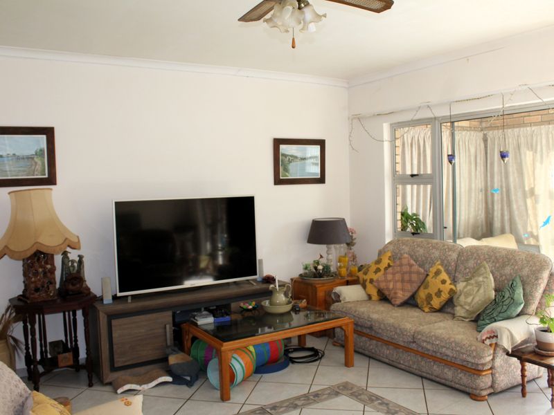 A living room featuring ceramic floor tiles, a ceiling fan, and a large sliding glass door providing access to the outdoor area.