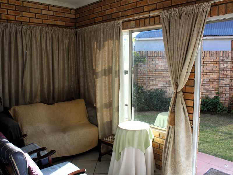 Enclosed patio area featuring exposed brick walls, tiled flooring, and a sliding glass door providing direct access to the rear garden.