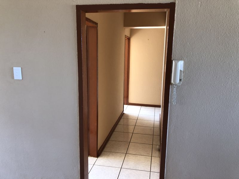 A functional hallway featuring tiled flooring and a wall-mounted intercom system, connecting various rooms within the apartment.