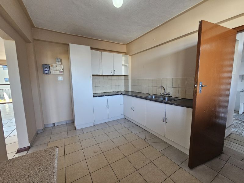 A functional kitchen space featuring built-in white cabinetry, laminate countertops, a double bowl sink, and tiled flooring, ready for a modern renovation.